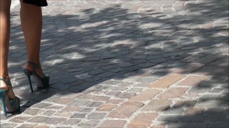 Outdoors candid film of a woman with sexy legs and feet in platform high heels walking around and sitting on a bench to rest her feet.